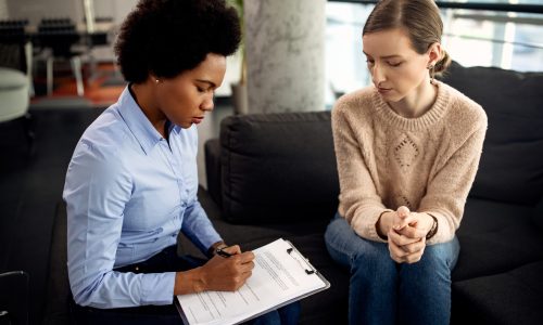 African American psychotherapist writing notes during a session Individual sitting with a counsellor in individual sessions to Understand the Role of Individual Counselling in Improving Relationships