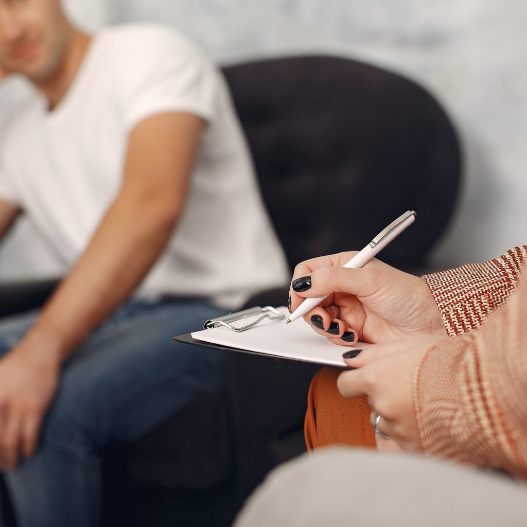 Man sitting in the psychologist’s office and talking about probl Male client sitting in counselling for individual counselling for relationship challenges.